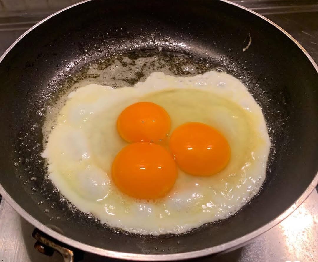 Three fresh free-range eggs frying in a pan
